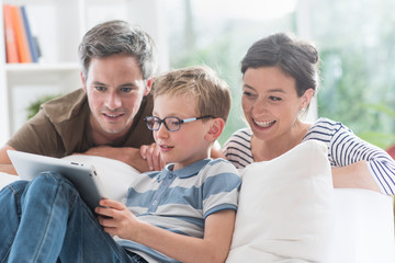 a cheerful family has fun together by playing on a tablet