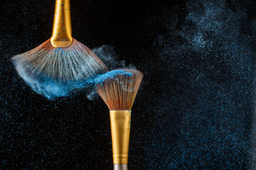 Two brushes and blue feathered shadows at black background