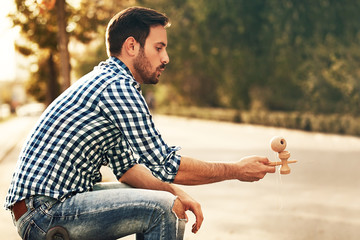 Young man enjoying outside and playing by kendama.