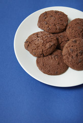 A plate full of chocolate chunk cookies on a blue background forming a page border