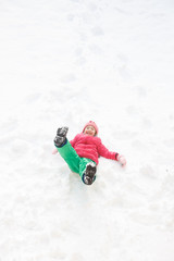 Fototapeta na wymiar Playful girl with braids playing in the first snow