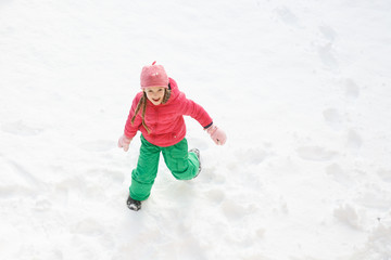 Fototapeta na wymiar Playful girl with braids playing and running in snow