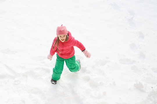 Playful girl with braids playing and running in snow