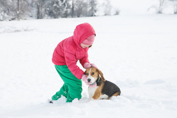 Little girl playing with her dog in a snowy landscape