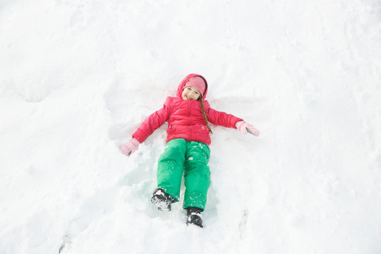 Playful girl playing in snow, making a snow angel