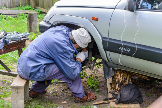 The man repairs car in the field.