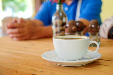 White coffee cup on wooden table with blurred man background.