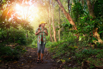 happy traveler with backpack hiking in rain forest.