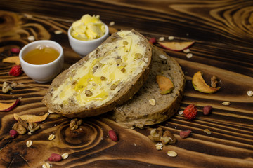 Two slices of bread and a cup of honey and butter, peanuts and decorated with pieces of dried apple lying on a wooden background
