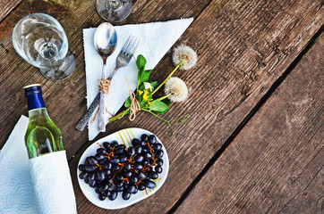 bottle of white wine, grapes, glass wine glasses on an old wooden background, romantic dinner under the stars