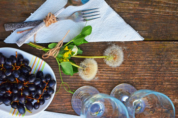 bottle of white wine, grapes, glass wine glasses on an old wooden background, romantic dinner under the stars