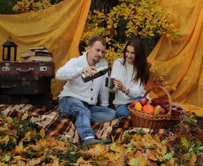 семейная пара в осеннем лесу на пикнике наливают чай в чашку