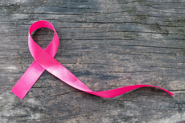 Breast cancer awareness campaign with pink ribbon on wood background (clipping path) Satin fabric...