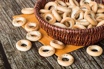  Small drying with poppy seeds.   Small drying with poppy seeds in a wicker basket on a napkin on gray wooden table.
