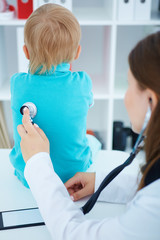 Fototapeta premium Ill child auscultated by young female pediatrician. Paediatrics medical concept.