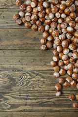 Whole hazelnuts arranged on a rustic wooden background to form a page border