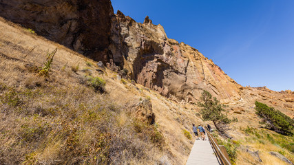 The path among the rocks. The sheer rock walls. Beautiful landscape of yellow sharp cliffs. Dry yellow grass grows on the slopes of the mountains. Smith Rock state park, Oregon