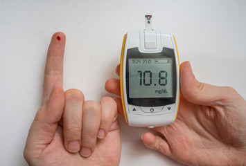Diabetic patient is using glucometer to check glucose level. Blood on finger.