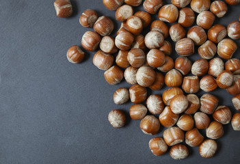 A pile of whole hazel nuts arranged on a rustic slate background to form a page border