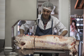 Butcher cutting carcass with bandsaw in butchery