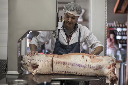 Butcher cutting carcass with bandsaw in butchery