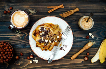 Healthy fall and winter breakfast. Vegan vanilla french toast with caramelized bananas, raw dark chocolate and hazelnut butter. Flat lay. Rustic country style. Ideal Christmas morning meal concept