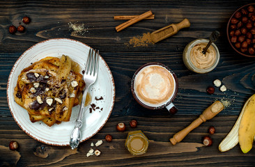 Healthy fall and winter breakfast. Vegan vanilla french toast with caramelized bananas, raw dark chocolate and hazelnut butter. Flat lay. Rustic country style. Ideal Christmas morning meal concept