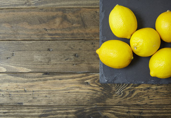 Lemons arranged on a slate and rustic wooden background forming a page border