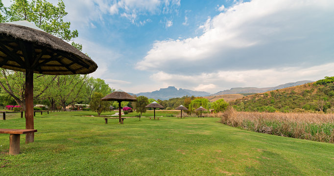 Thatched umbrellas in a park near Champagne Castle, with Cathkin Peak, part of the Drakensberg in the background