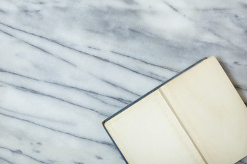 An open blank library book on a white marble desk top background arranged to form a page border