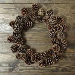 Pine cone wreath arranged on a rustic wooden background forming a page border