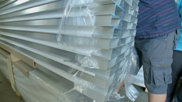 Three people are unwrapping some material that has been wrapped into a plastic wrap. They are tearing it down. Close-up shot.
