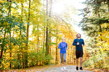 Obraz premium Beautiful couple running outside in sunny autumn forest