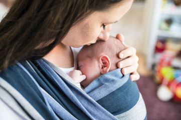 Unrecognizable young mother with her son in sling