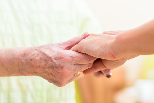 Altenpfleger hält Hand von Seniorin