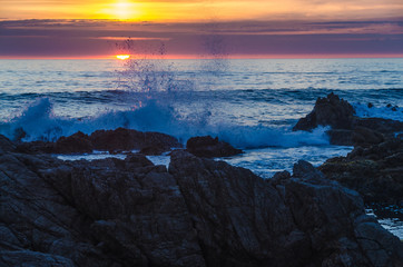 waves crashing against rocks at sunset over the sea