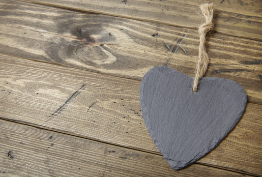 A blank slate heart shaped gift tag on a rustic wooden background