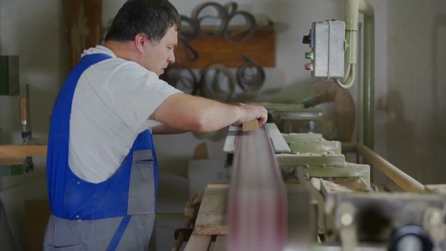 A belt sander is helping a carpenter with his work. He is designing the pieces of wood. Wide-angle shot.
