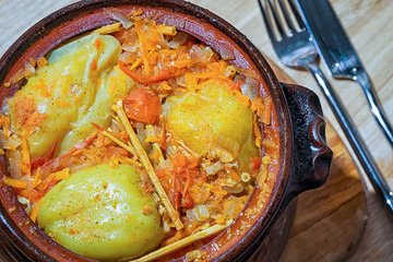 fragrant stuffed baked bell peppers in a clay pot, top view.
