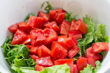 Healthy green salad, tomatoes in white bowl
