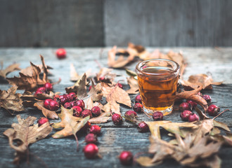 tincture of hawthorn in a glass transparent with autumn leaves on the wooden table