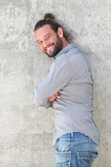 Smiling man leaning against wall with arms crossed