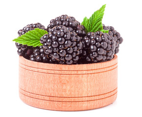 Blackberries with leaves in a wooden bowl isolated on white background