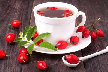 cup with rose hip tea on a dark wooden background