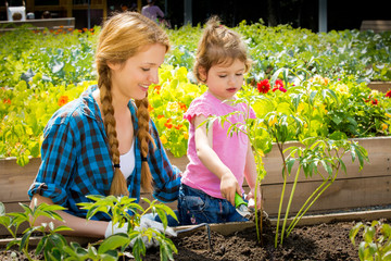 Woman with her little daughter in garden
Planting the flower