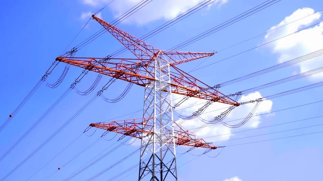 Strommast mit &Uuml;berland Stromleitung vor blauen Himmel und ziehenden Wolken