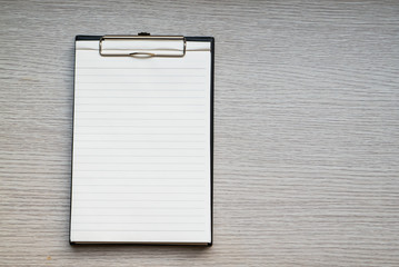 Blank paper in clipboard on wooden table with copy space