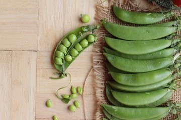 Fresh green peas pod on wood background.