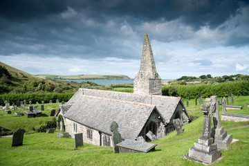 Fototapeta na wymiar Saint Enodoc Church on a stormy day with the Camel estuary and the Stepper Point in the background.
