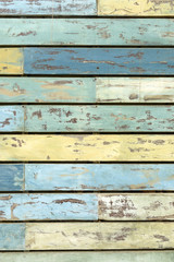 Weathered wood plank grunge background in chipped and peeling blue and yellow colored paint